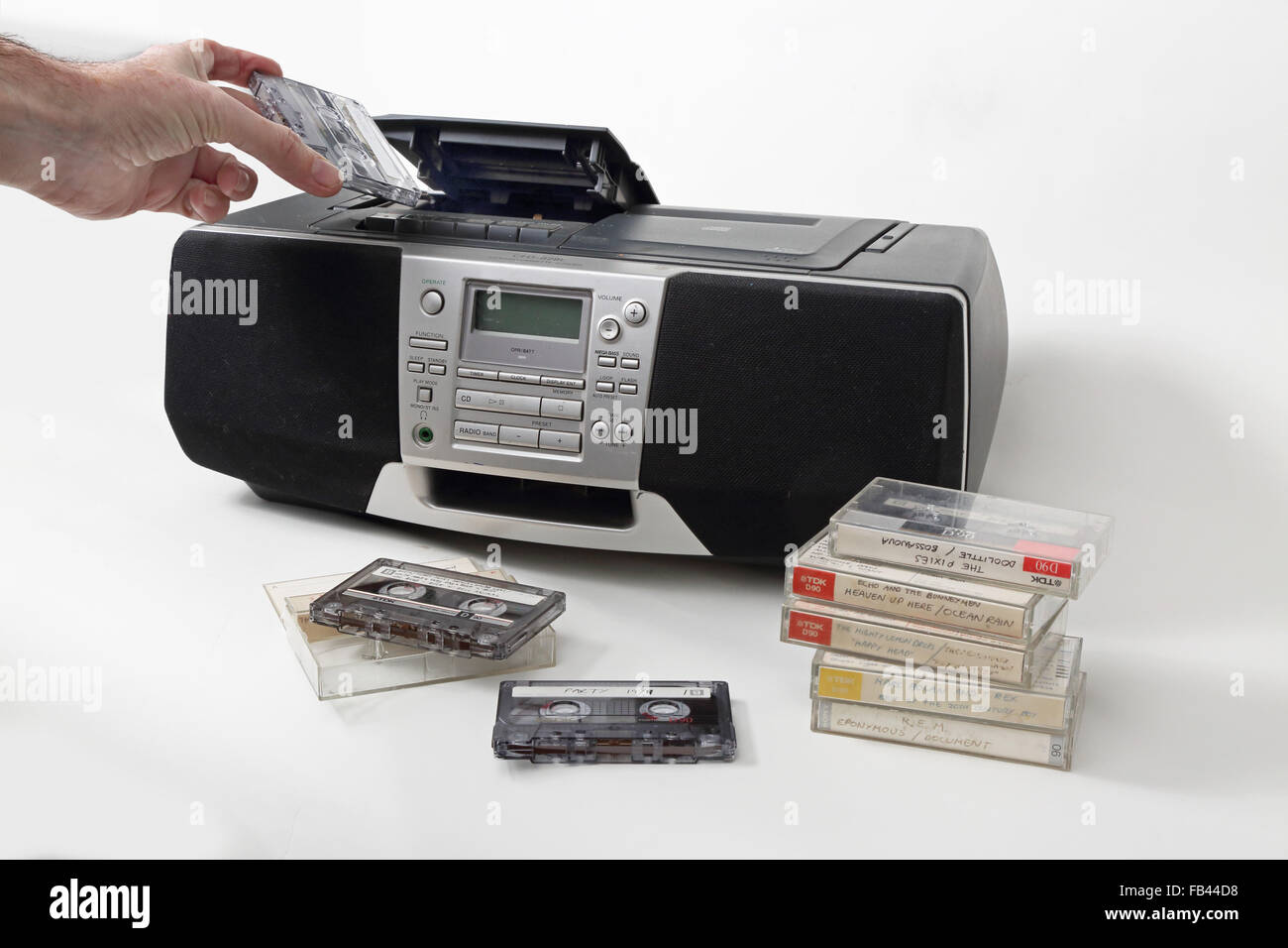 A home-recorded cassette tape is loaded into a1990s style cassette, radio and and CD player. Tapes stacked in the foreground. Stock Photo