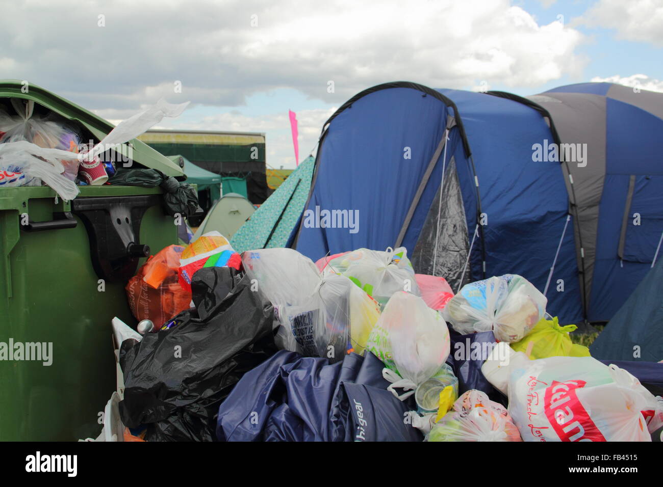 Rubbish overflows from a bin next to festival goers' tents on the final day of  the Y Not festival, Peak District, Derbyshire UK Stock Photo
