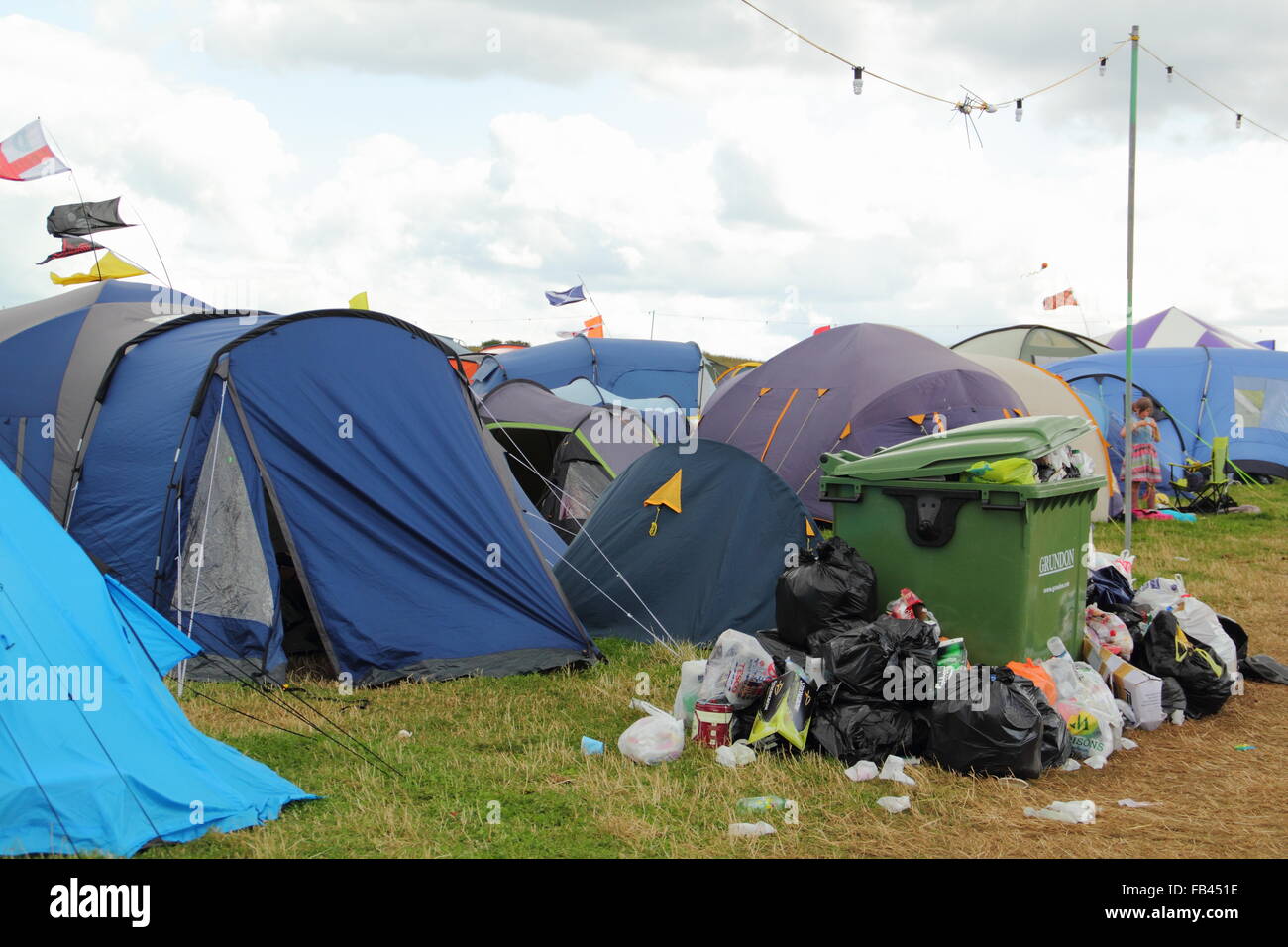 Rubbish overflows from a bin next to festival goers' tents on the final day of  the Y Not festival, Pikehall, Derbyshire UK Stock Photo