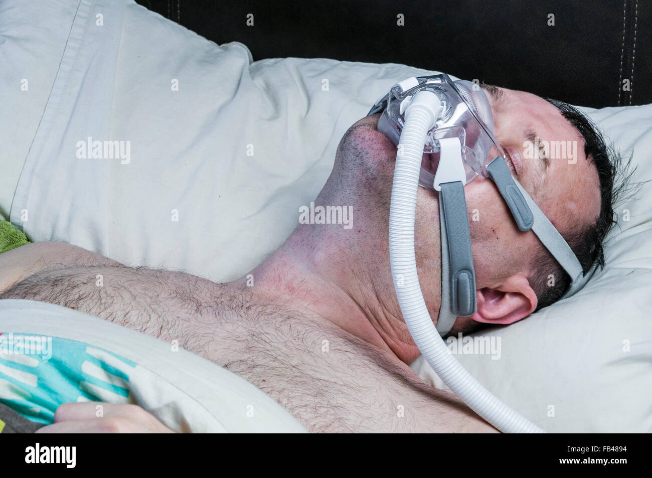 A middleaged, overweight man wearing a CPAP mask while sleeping in bed