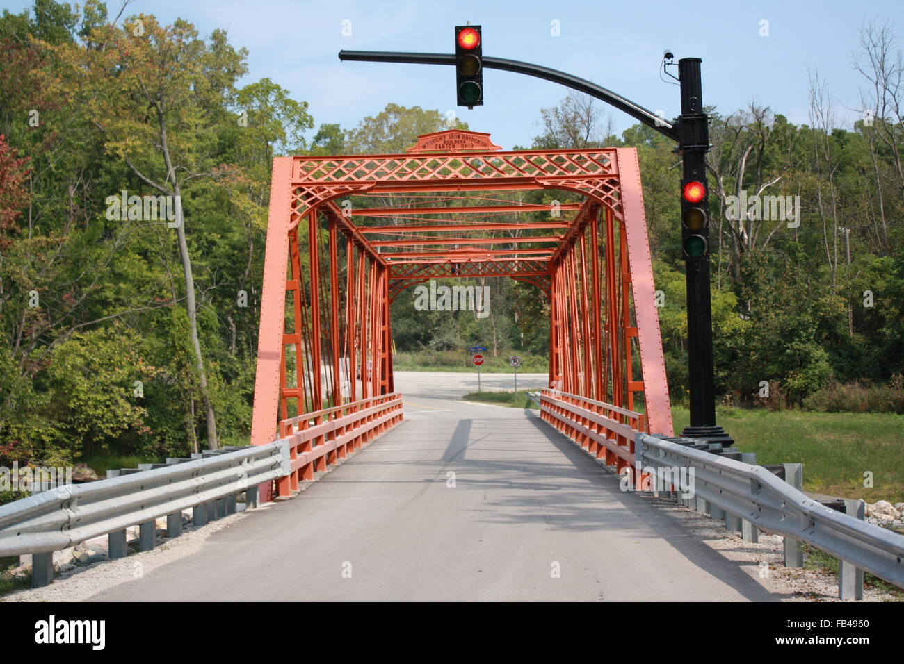 Red stoplight at orange truss iron bridge over Huron River near Ann Arbor, Michigan. Stock Photo