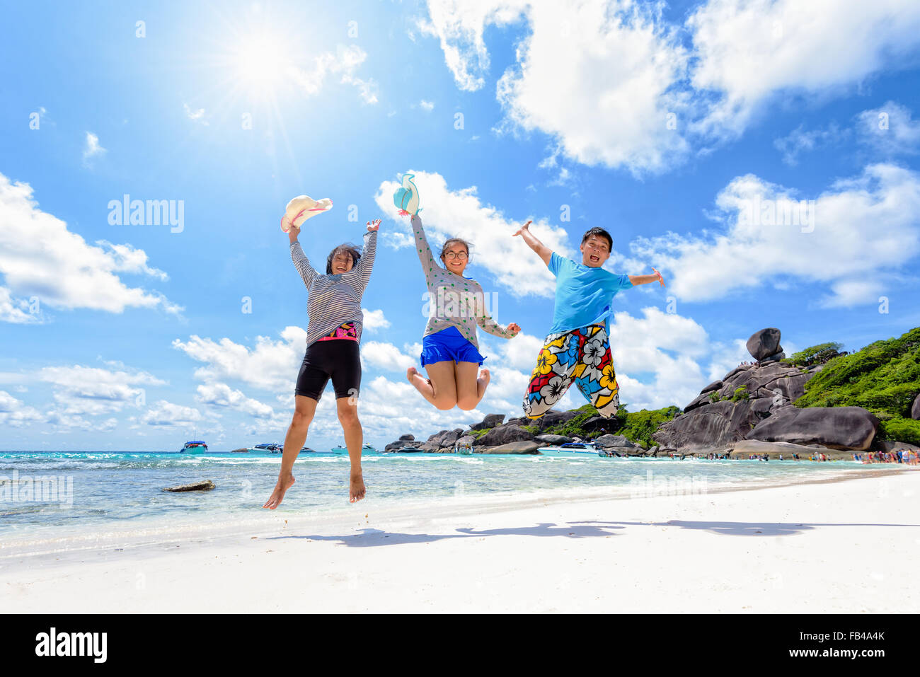 Family travels on vacation jumping with happy on beach near the sea under the sun blue sky and clouds of summer at Koh Similan Stock Photo