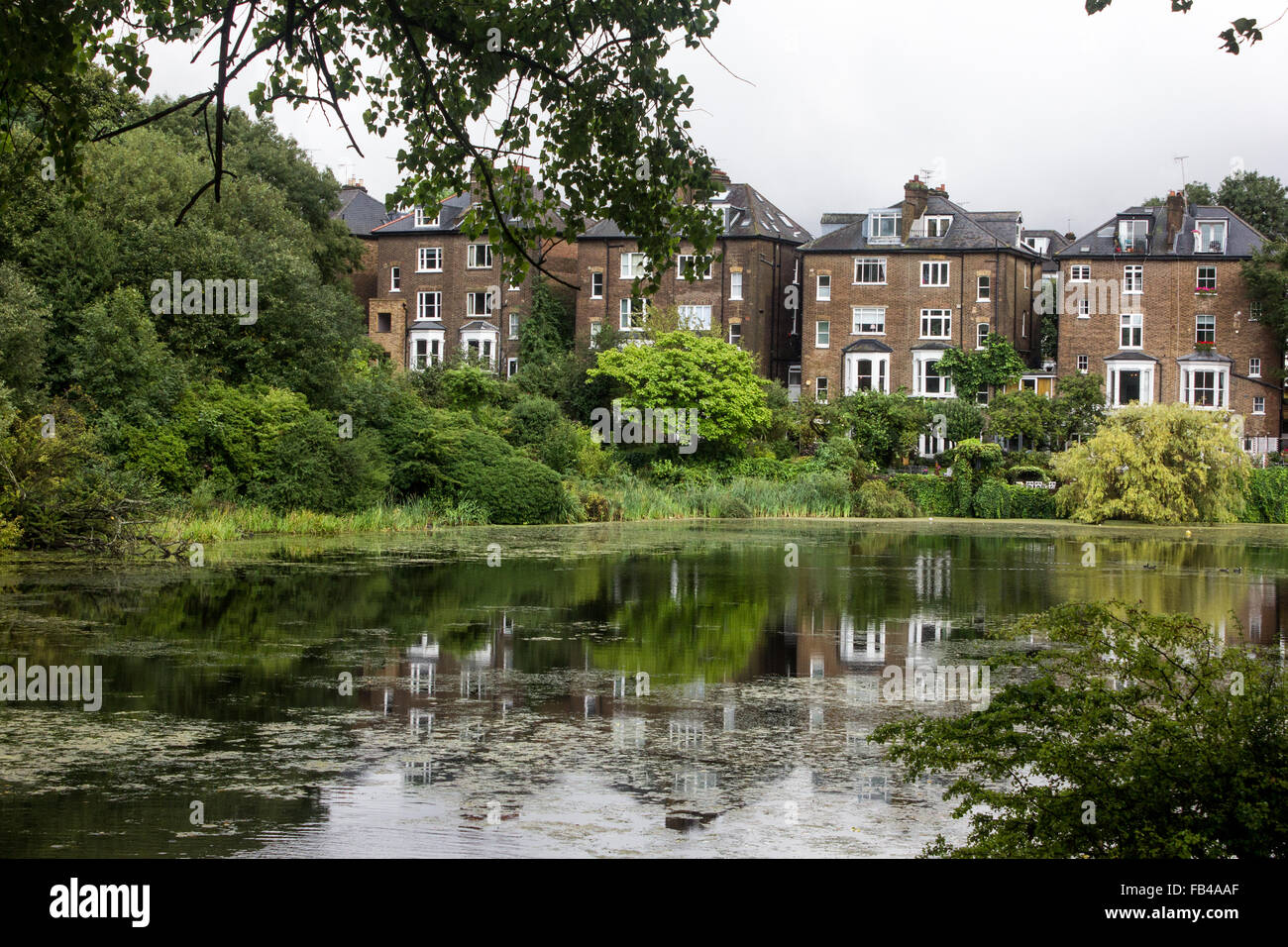 Houses overlooking a lake with a vivid reflection at Hampstead Heath