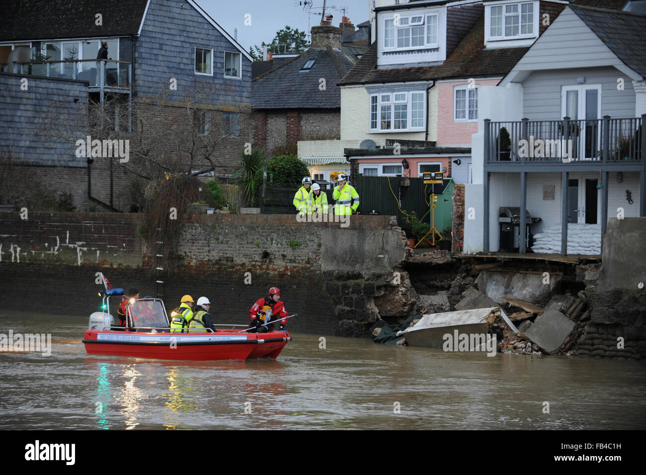 Members of the Environment Agency and the West Sussex Fire And Rescue Service inspect the damage to a river flood wall which collapsed along the River Arun in the historic town of Arundel in West Sussex, England. Stock Photo