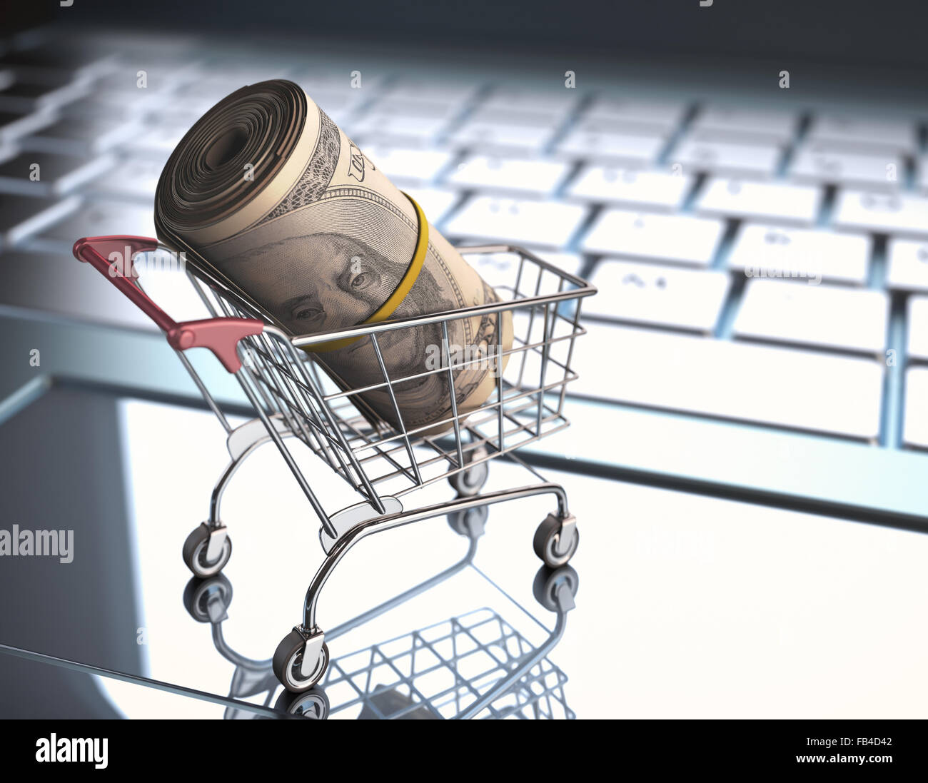 A roll of dollar bills in a shopping cart over a laptop keyboard. Stock Photo