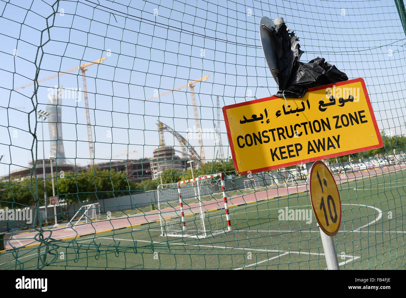 A sign reading 'Construction Zone - Keep Away' stands at an entrance to the construction site of the Khalifa International Stadium in Doha, 09 January 2016. The stadium is currently undergoing renovation works. The Khalifa International Stadium is the first proposed host venue for the 2022 FIFA World Cup Qatar. In background at left is the hotel 'The Torch'. Photo: Andreas Gebert/dpa Stock Photo