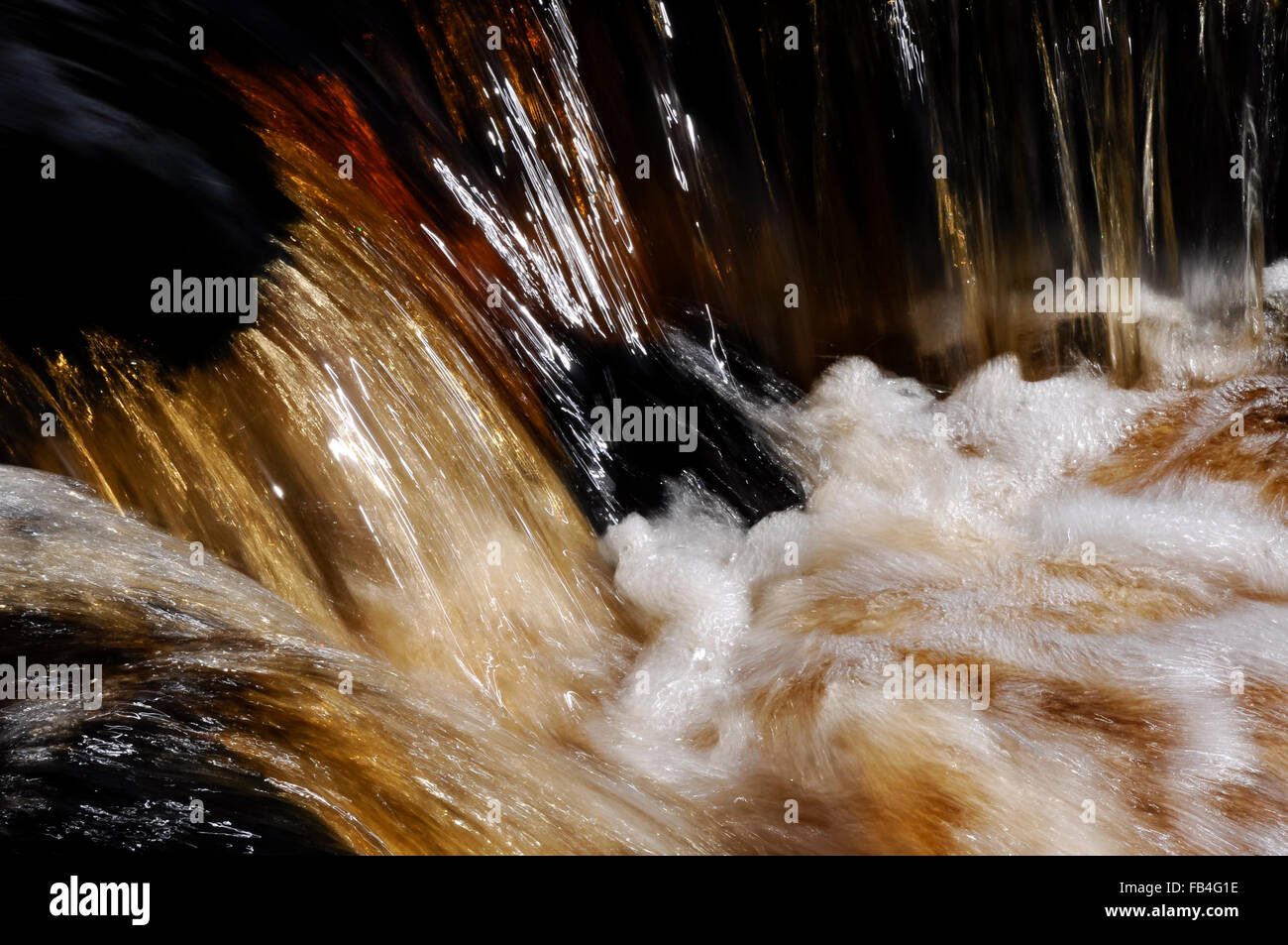 Abstract image of peaty coloured water flowing in a moorland stream. Stock Photo