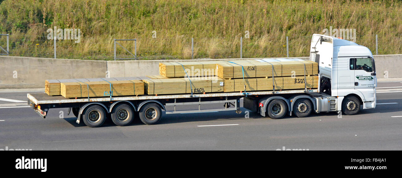Lorry with articulated trailer loaded with timber driving along Stock
