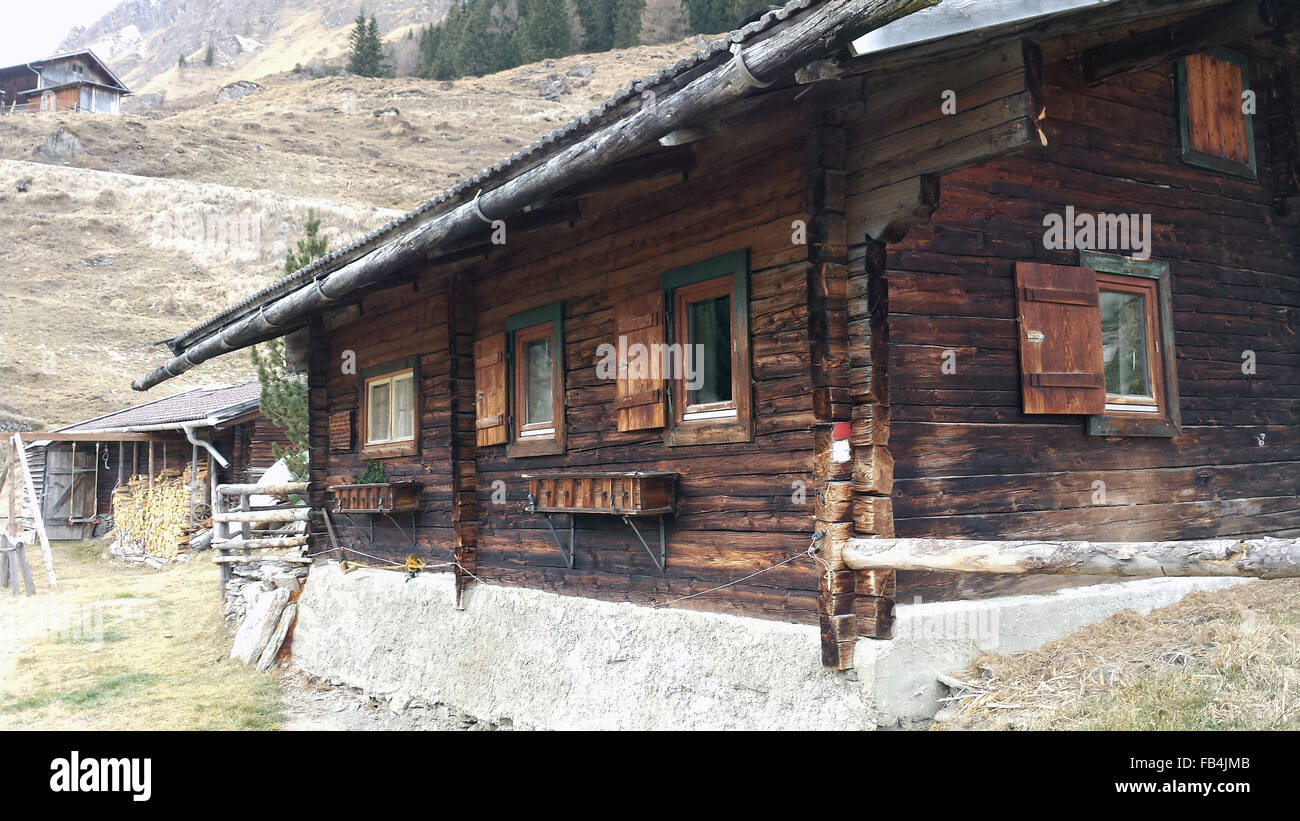 This  2015 photo shows an old farmhouse in Hintertux, the area of the Hintertux Glacier at the far end of the Zillertal (Ziller Valley) in the Tirol, Austria. Note the windows at far left are modern; the others have the traditional wood coverings. The window boxes are empty as the time of year is winter—an mild one with no snow in the valley. Stock Photo