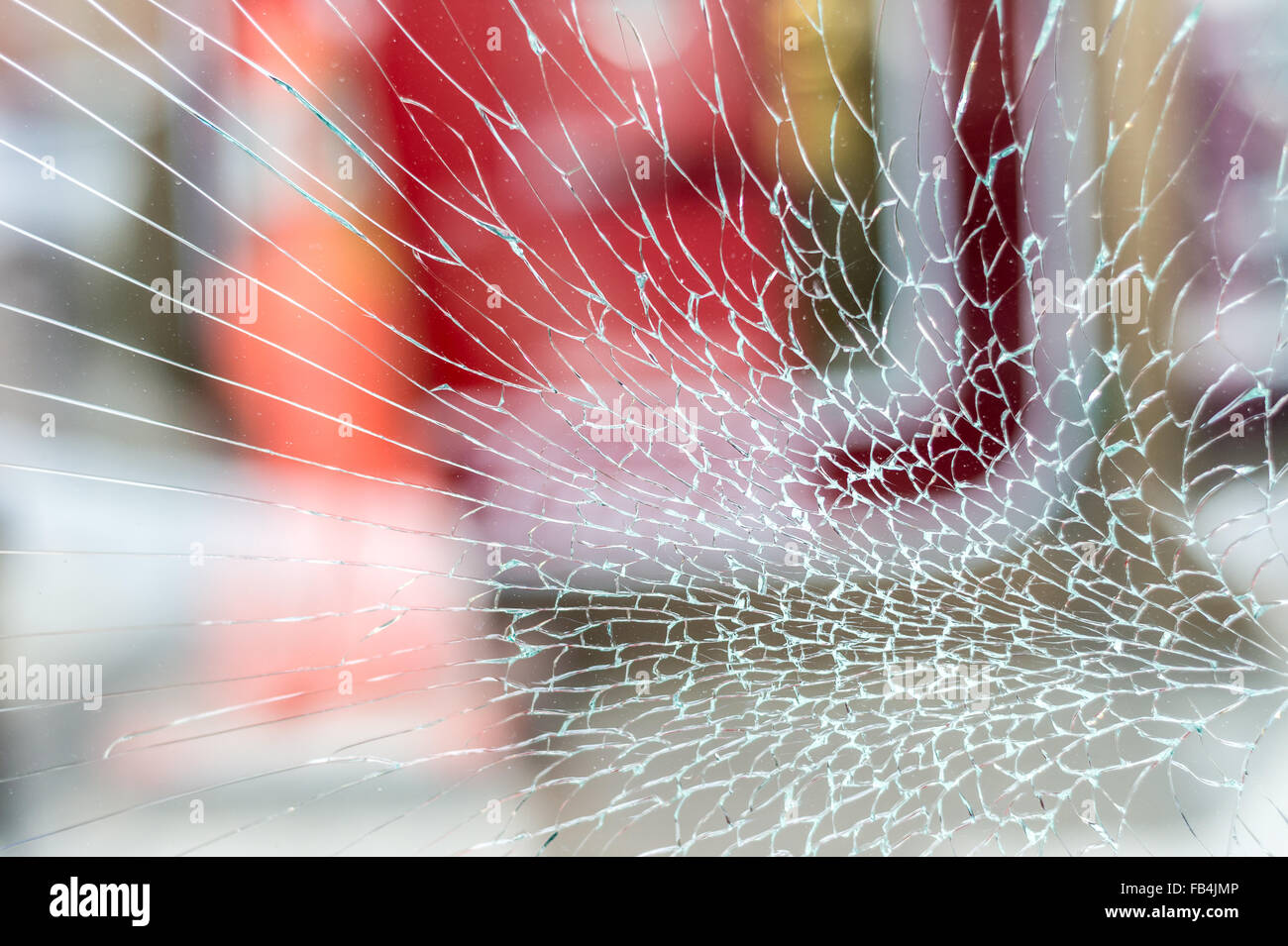 Cracked Shop Window Glass looking like a spider web, with red background Stock Photo