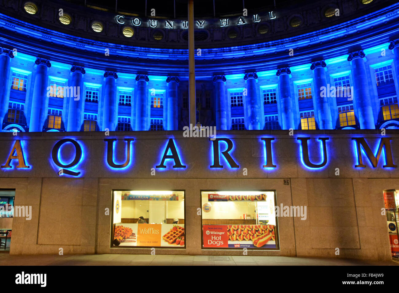London Aquarium illuminated sign above café windows with floodlighting on the old County Hall building on the Thames embankment England UK Stock Photo