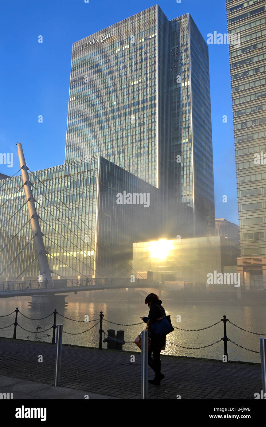 J P Morgan tower block seen above winter fog at Canary Wharf waterways with sun reflecting on glazing London Docklands Isle of Dogs England UK Stock Photo