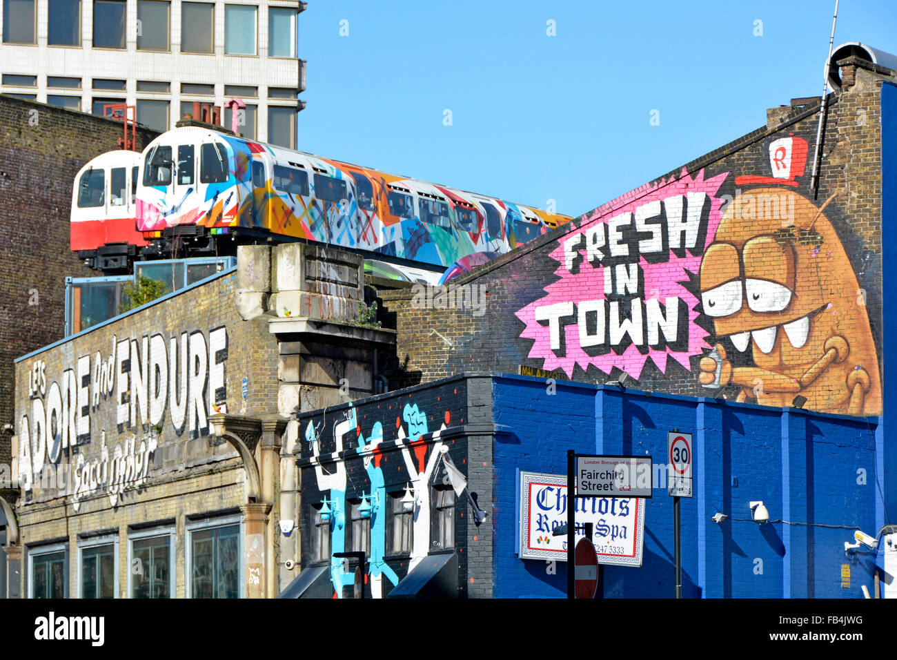 Recycling train carriages as artists studios on top old railway viaduct walls used for arty graffiti village underground Shoreditch London England UK Stock Photo