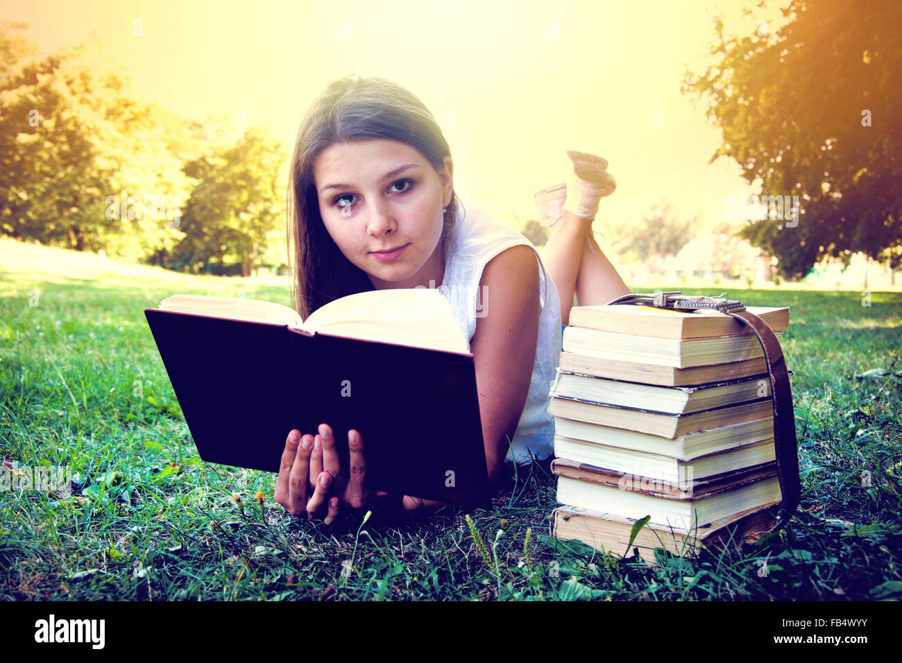 Student girl reading a book on campus grass. Education conceptual image. Instagram vintage picture. Stock Photo