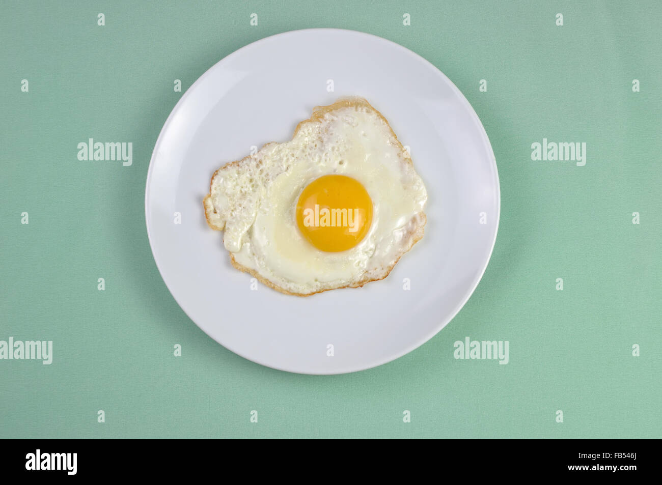 Fried eggs on a white plate and green background Stock Photo