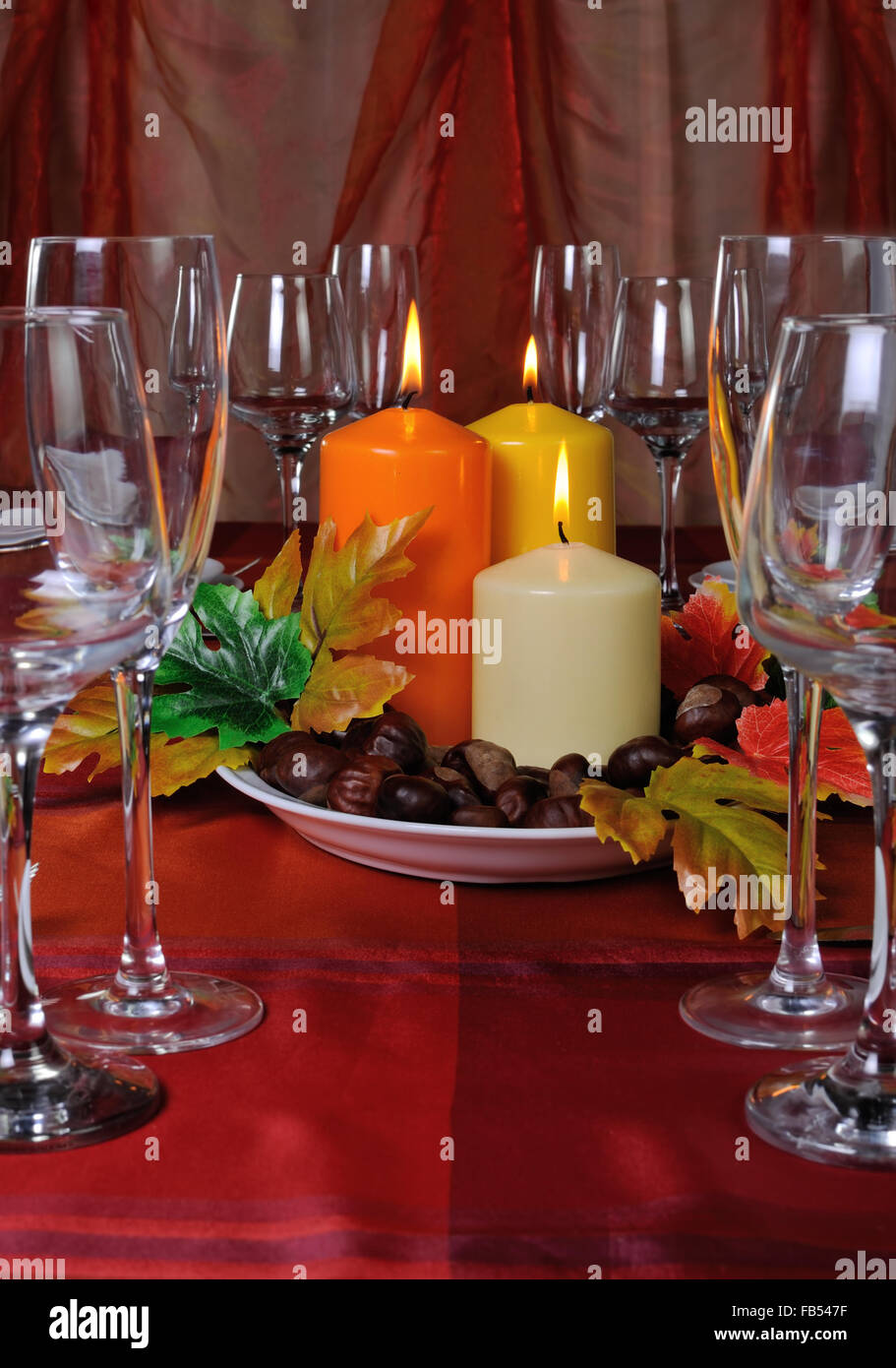 Candles as part of table setting with chestnuts in the autumn leaves ...