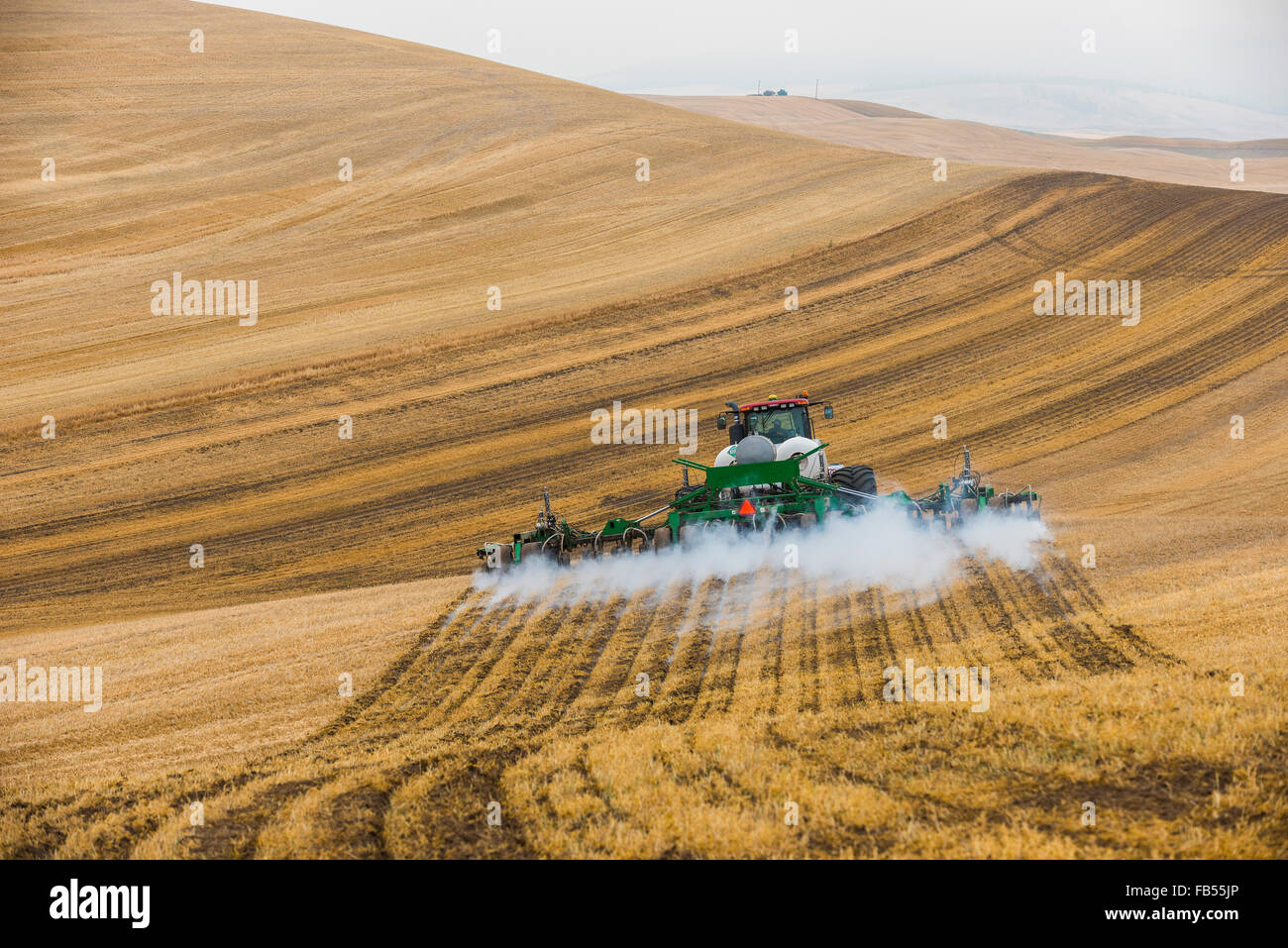 Case quadtrac tractor pulling an anhydrous ammonia tank and applicator applying the anhydrous to a field in advance of preparing Stock Photo