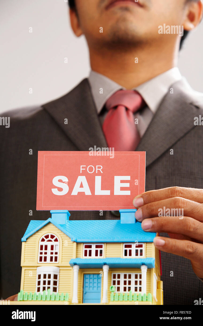 real estate agent holding a sign of for sale and a model house Stock ...