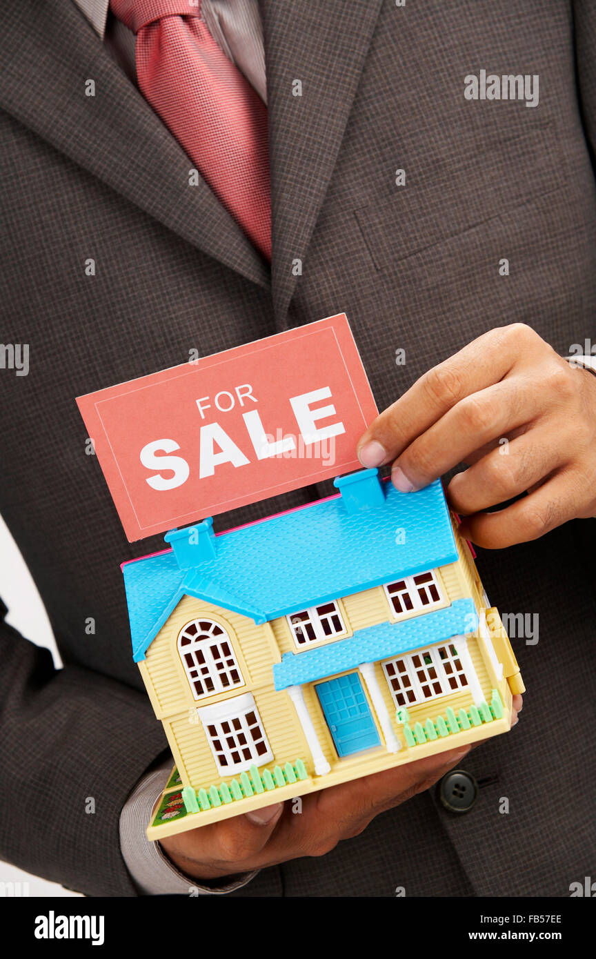 real estate agent holding a sign of for sale and a model house Stock ...