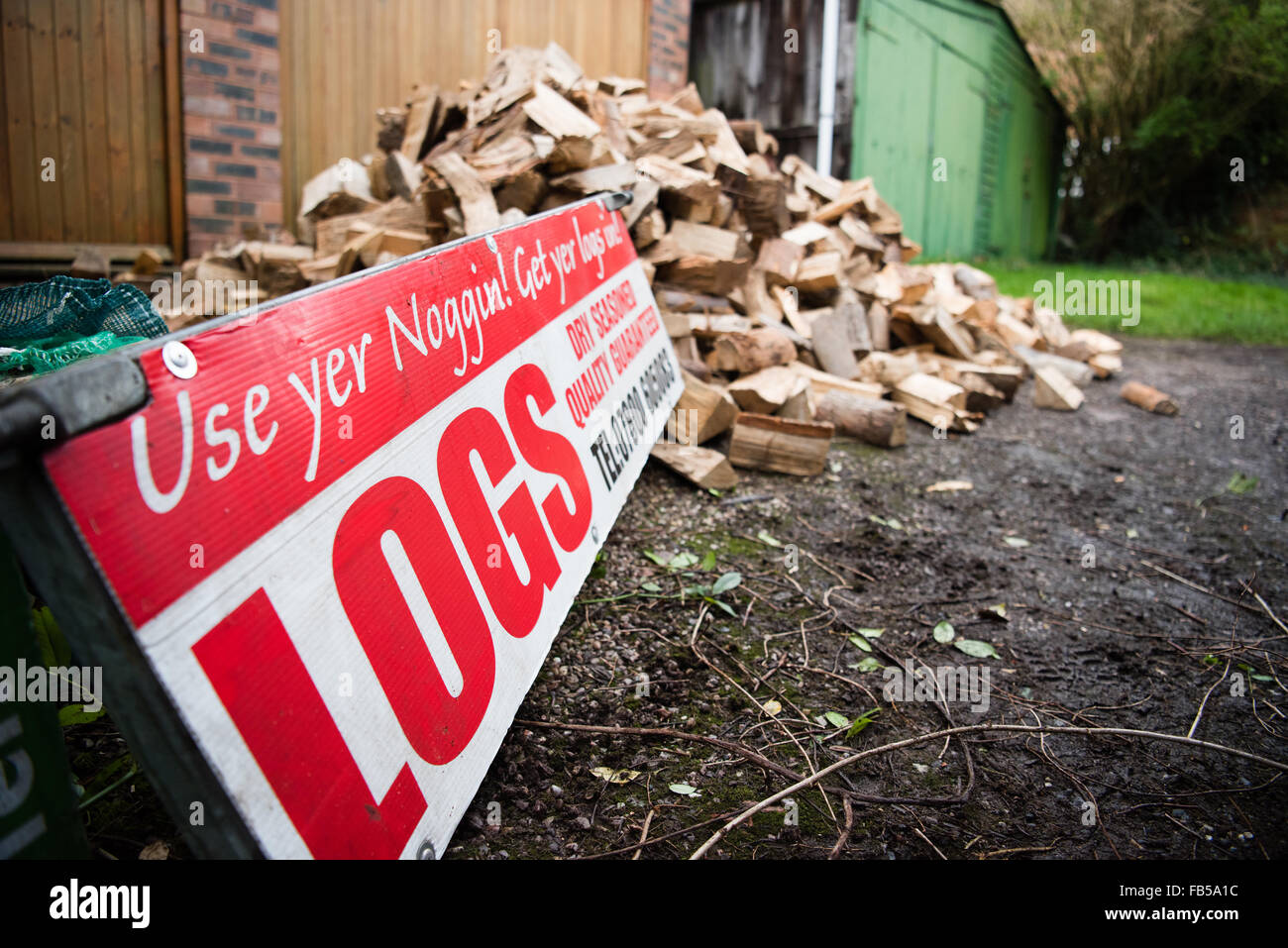 Sign selling logs for fires and woodburners near a great big pile of