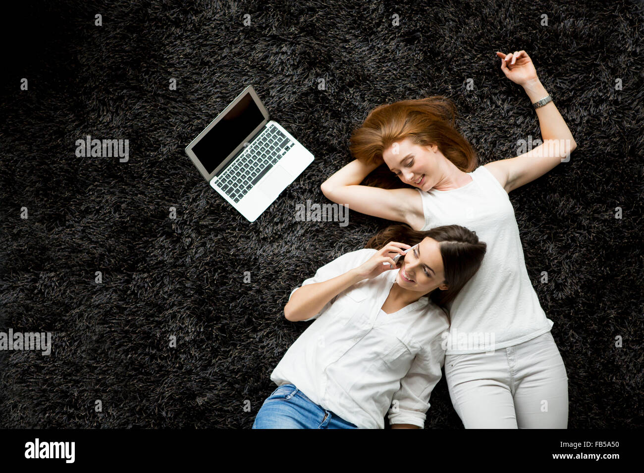 Young women laying on the carpet with laptop Stock Photo