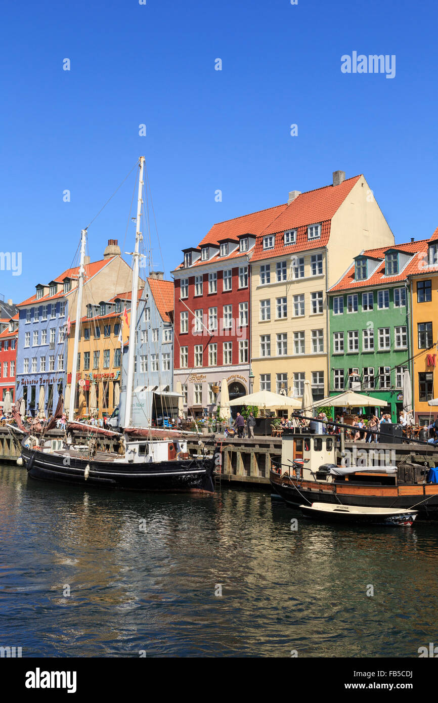 Old wooden boats moored on canal quay with colourful buildings on waterfront in summer. Nyhavn Copenhagen Denmark Scandinavia Stock Photo