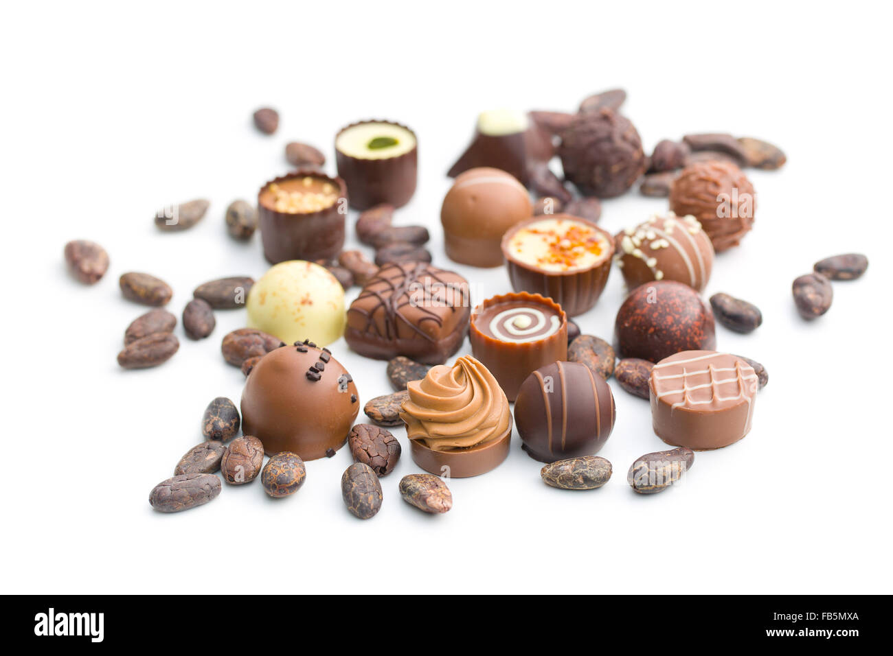 various chocolate pralines and cocoa beans on white background Stock Photo