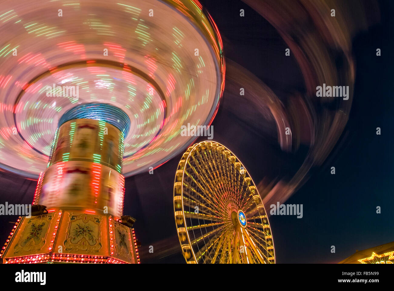 Funfair with giant wheel and merry go round in motion evening light germany europe Stock Photo
