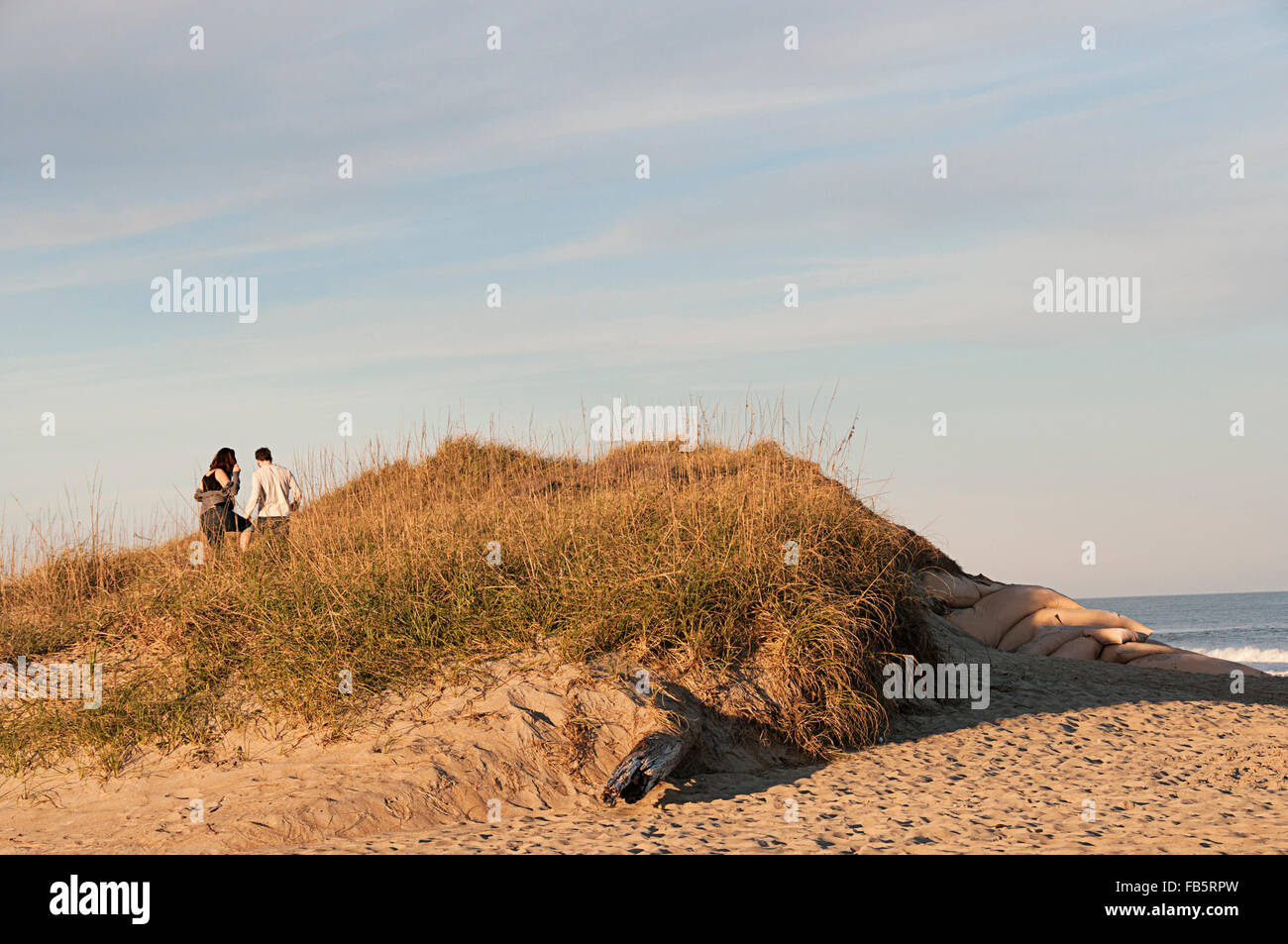 A couple climbing on a sand dune on Cape Hattaras, North Carolina in the Outer Banks. Stock Photo
