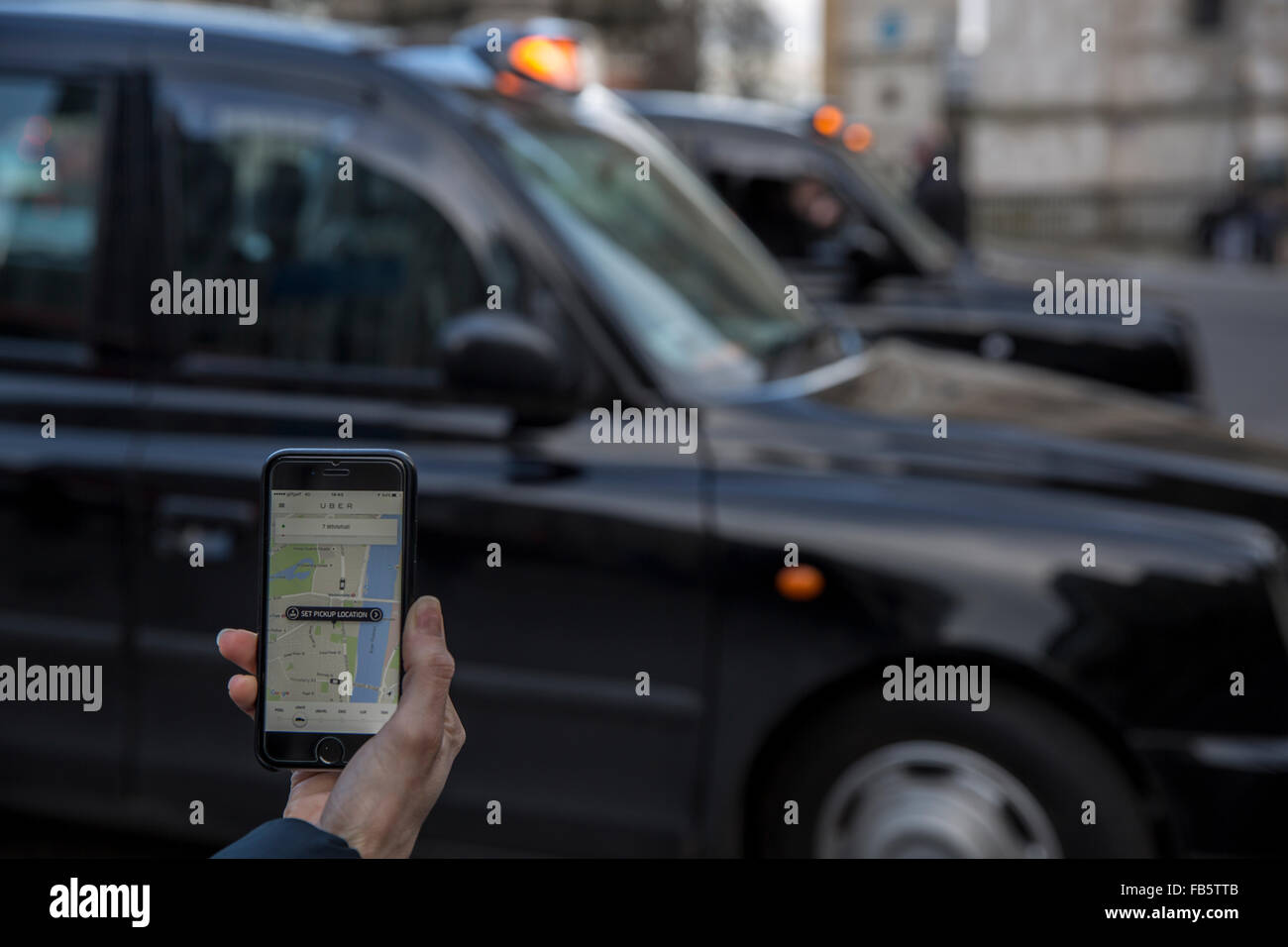 Uber App on Mobile with London Black Cabs in background Stock Photo