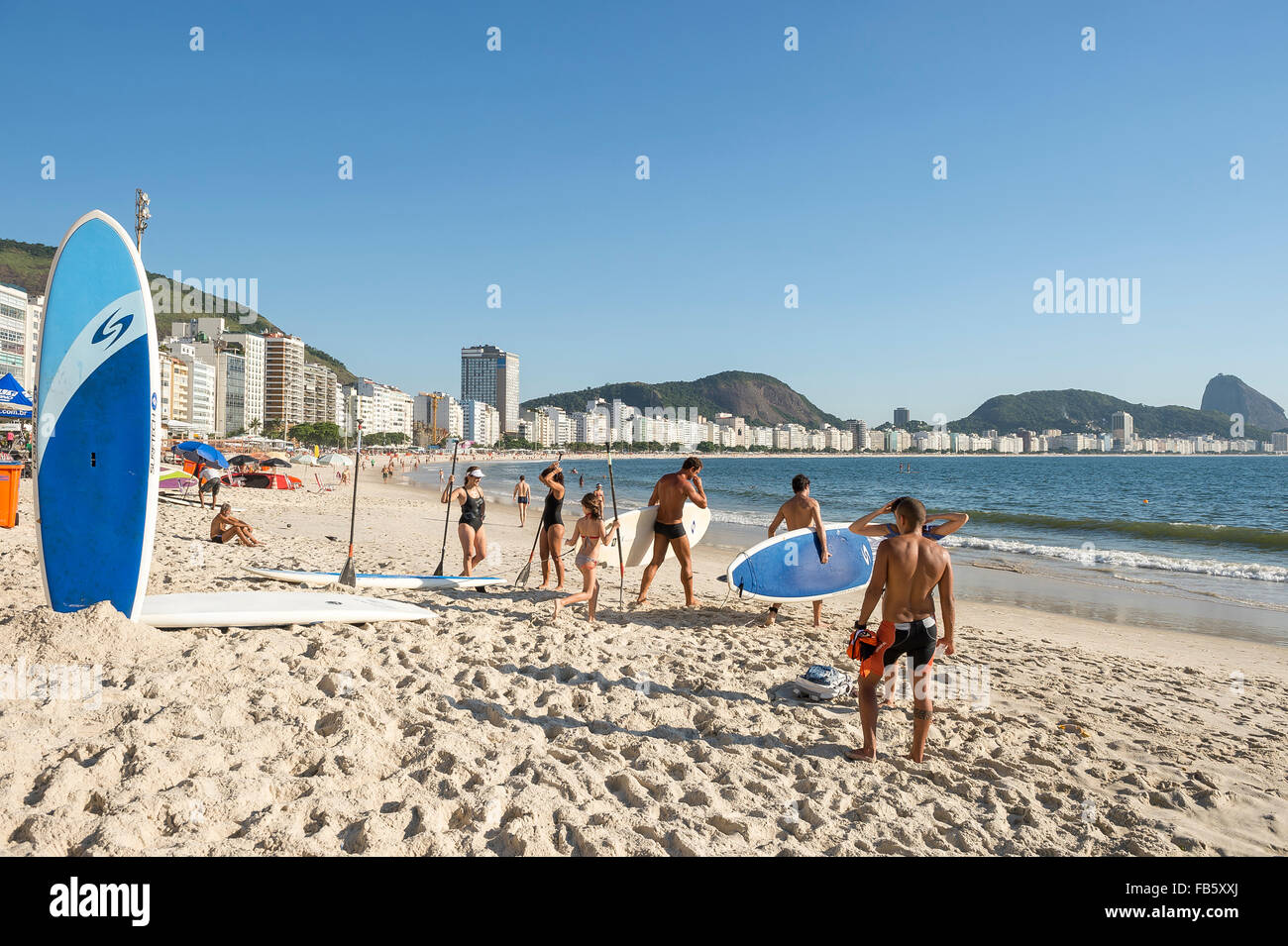 RIO DE JANEIRO, BRAZIL - FEBRUARY 05, 2014: Stand up paddlers carry their surfboard to the sea on a tranquil morning Copacabana. Stock Photo