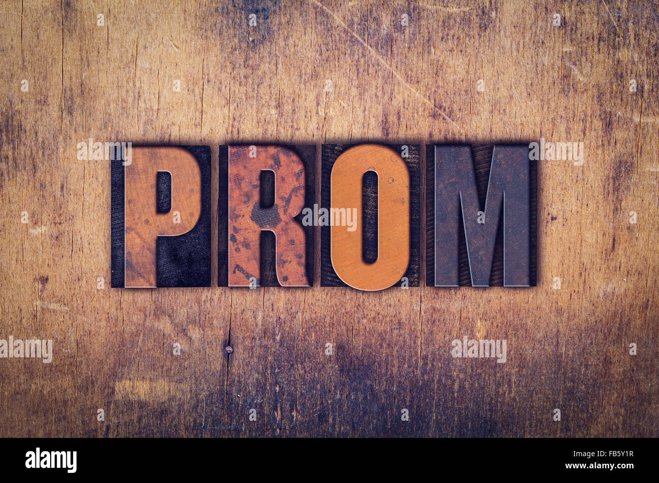 The word 'Prom' written in dirty vintage letterpress type on a aged wooden background. Stock Photo