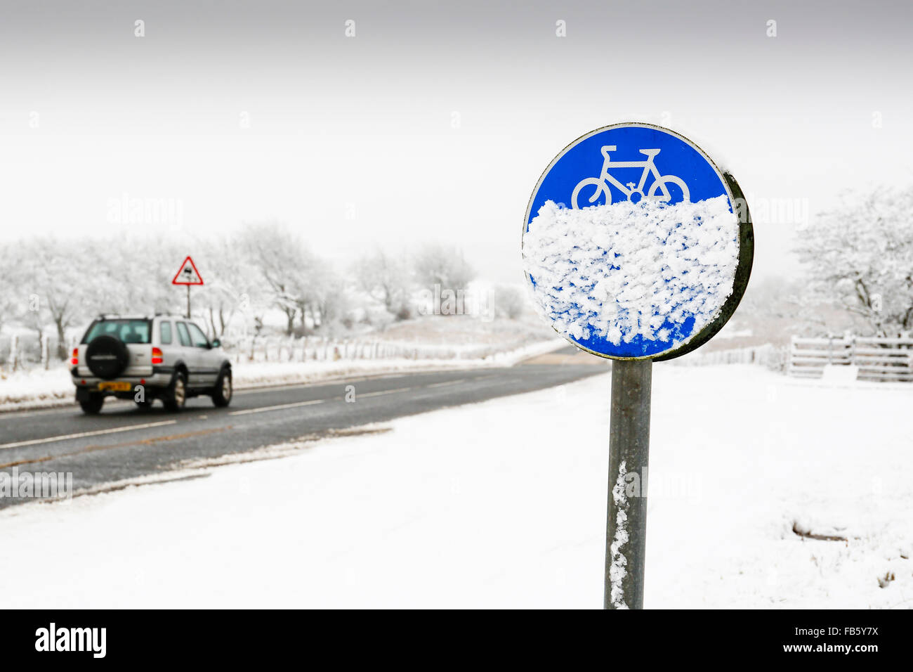 Vehicle driving on a country road in dangerous snowing conditions, with the cycle track covered in snow, Ayrshire, Scotland, UK Stock Photo