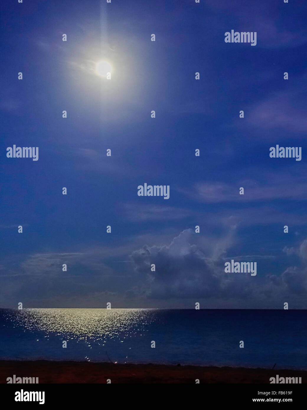 A full moon at night shines over the Caribbean casting a glow on the sea off St. Croix, U.S. Virgin Islands. Stock Photo