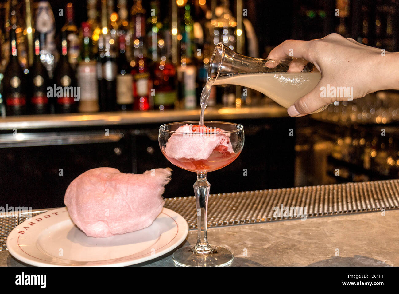 Demonstration of how to make a Pink Cashmere drink using a mix of juices and vodka poured over cotton candy. Stock Photo