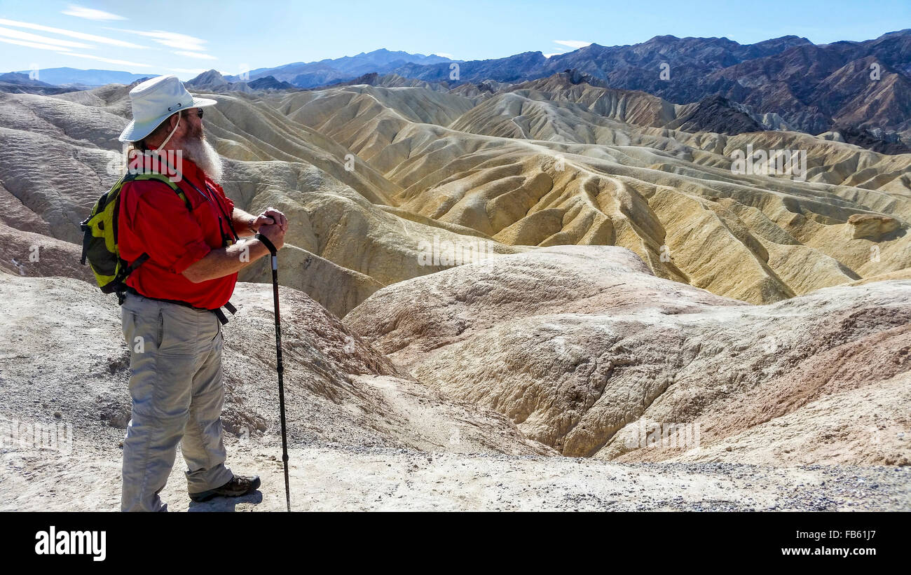 Man enjoys view from Death Valley's famous Zabriskie Point of surrounding desert hills. Stock Photo
