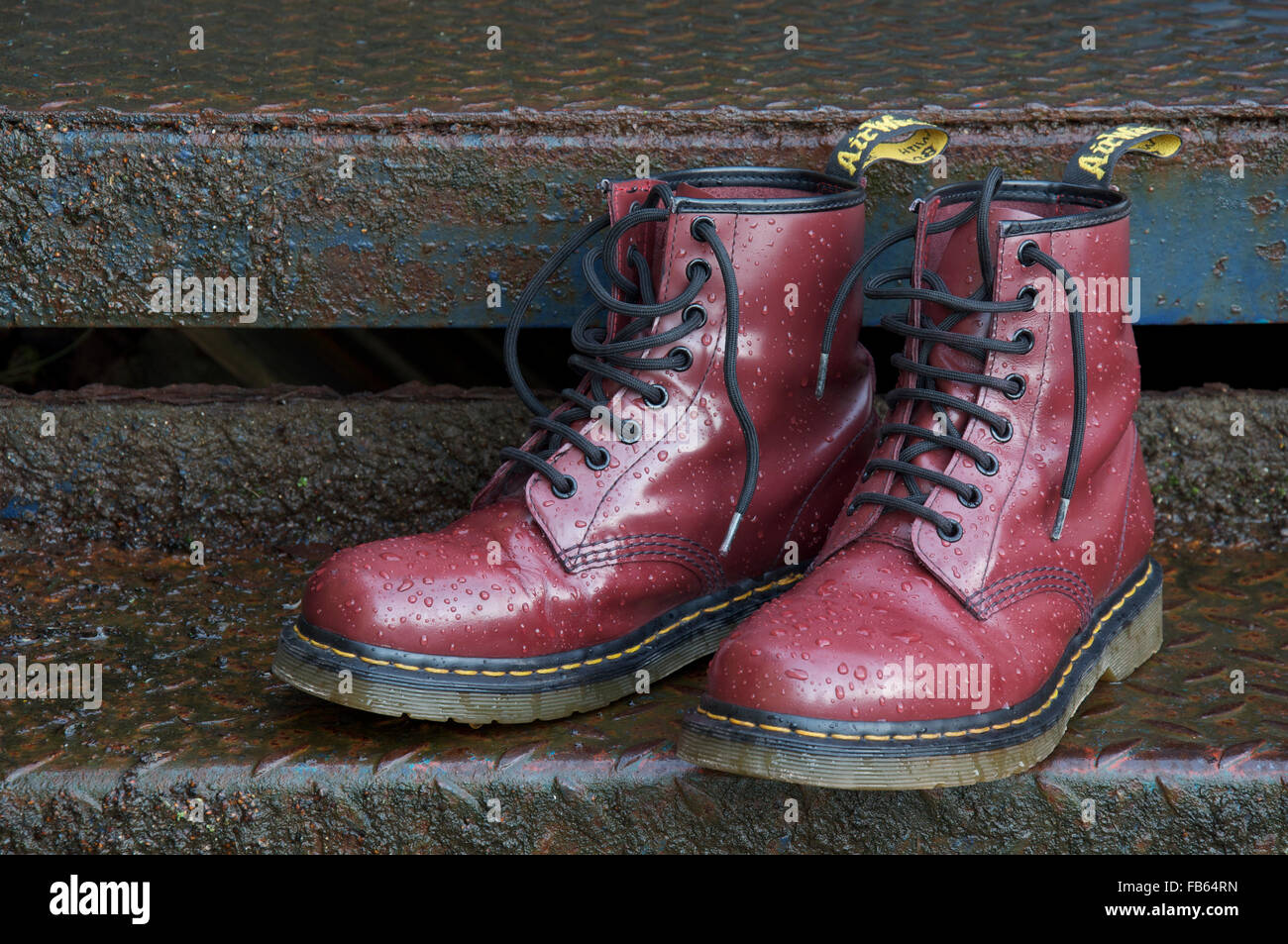 A pair of iconic cherry red, eight hole, Doc Marten lace-up boots, with  classic yellow stitching. On a wet rusty metal surface. United Kingdom  Stock Photo - Alamy