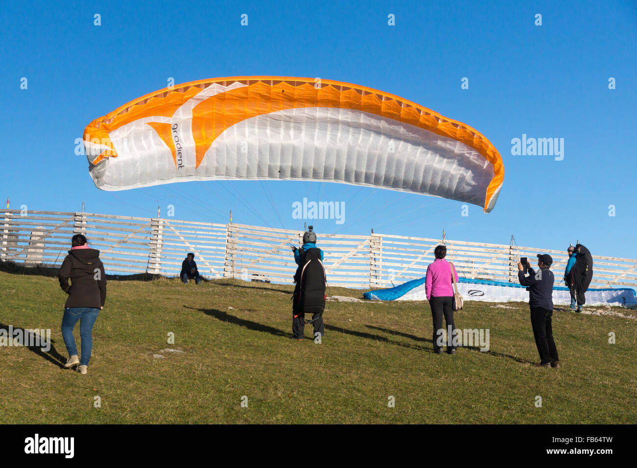 A paraglider, watched by onlookers, prepares for a reverse launch off ...