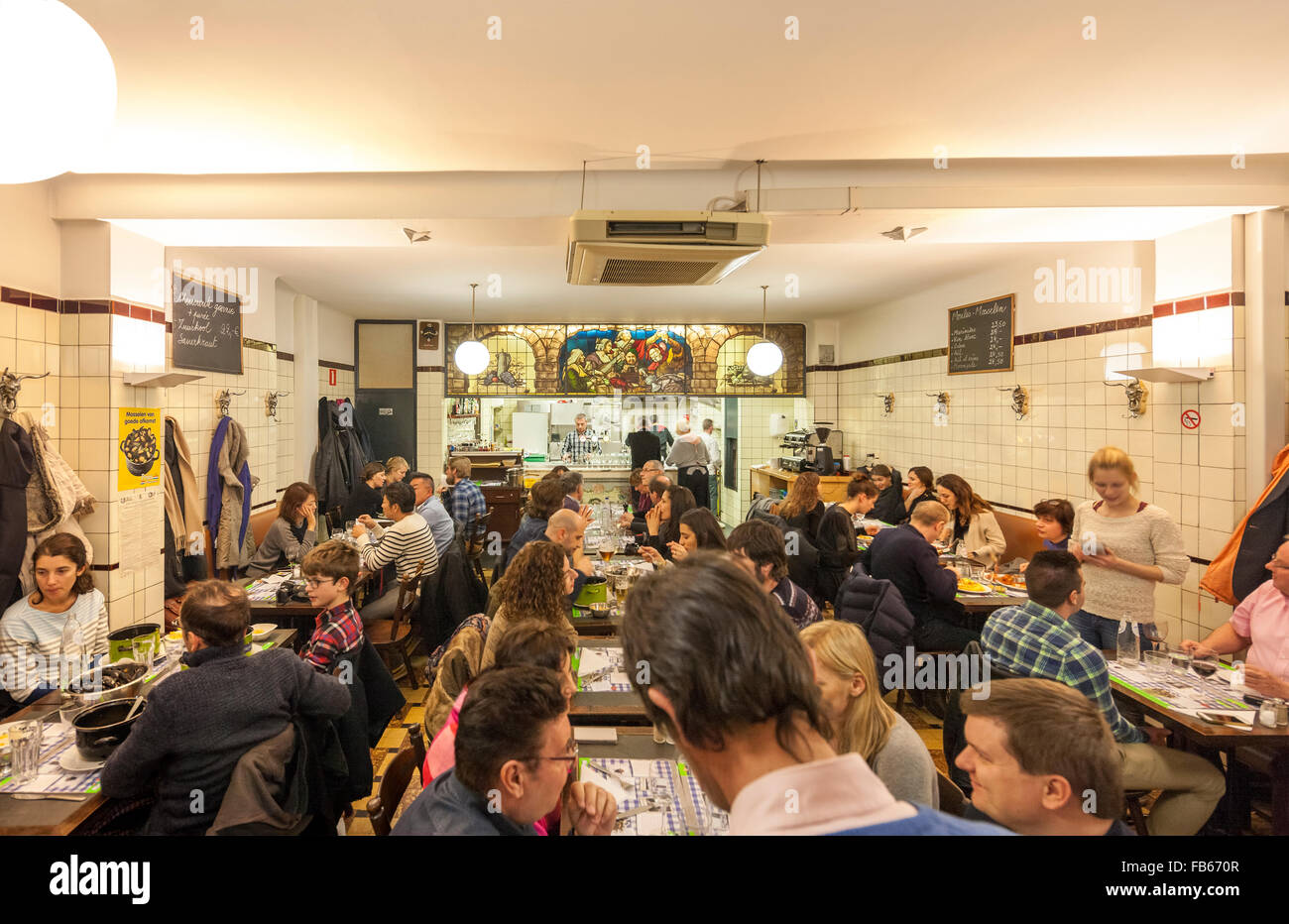 Brussels Restaurant Le Pré Salé interior with people eating mussels fries chips moules frites and other traditional Belgian food Stock Photo