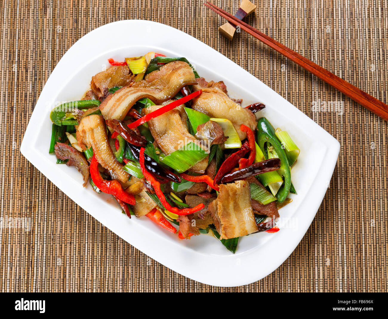 Top view of bacon, beef, peppers and onion in white plate with bamboo mat underneath. Stock Photo