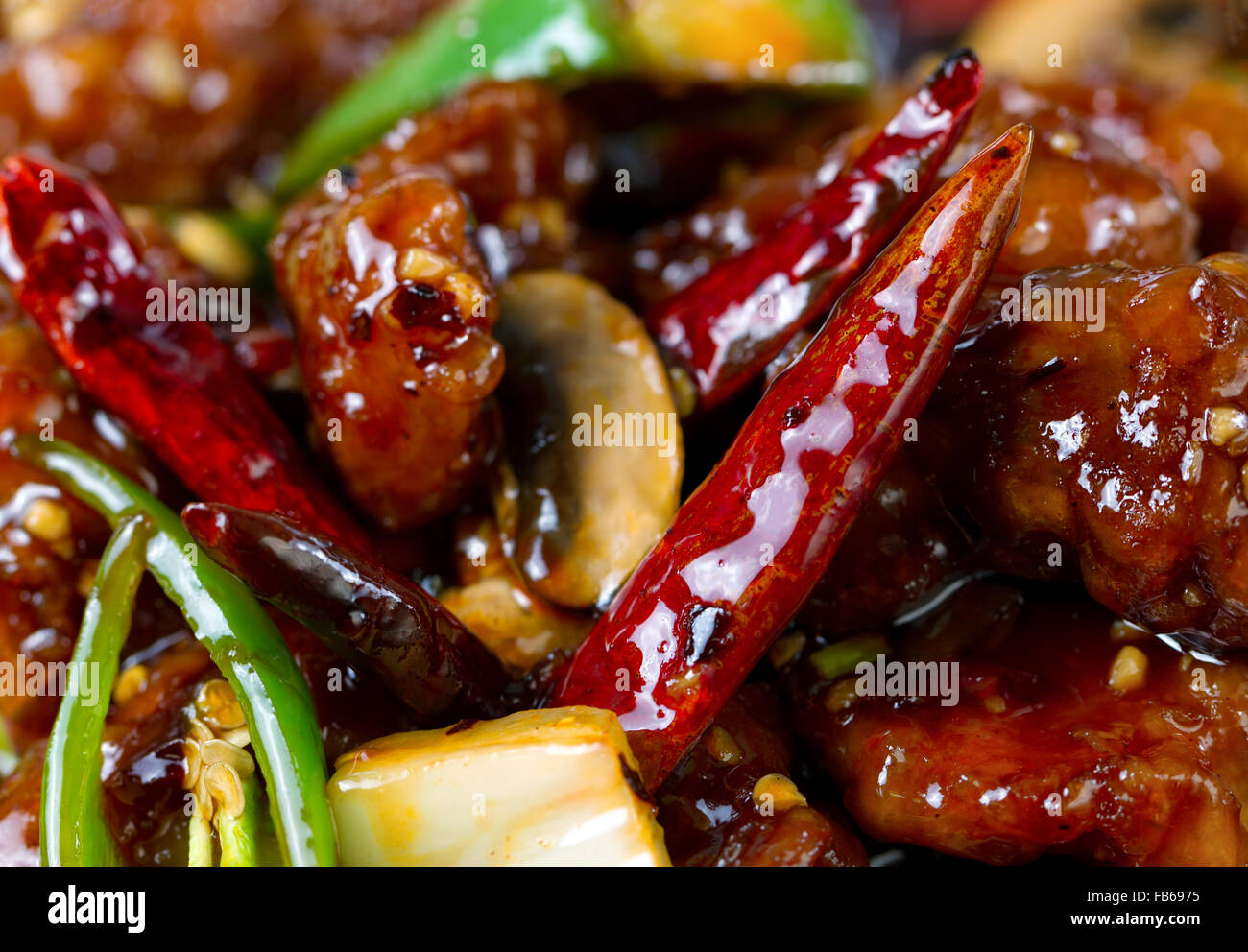Chinese hot red Chile peppers with chicken and vegetables. Filled frame format with selective focus on front pepper. Stock Photo