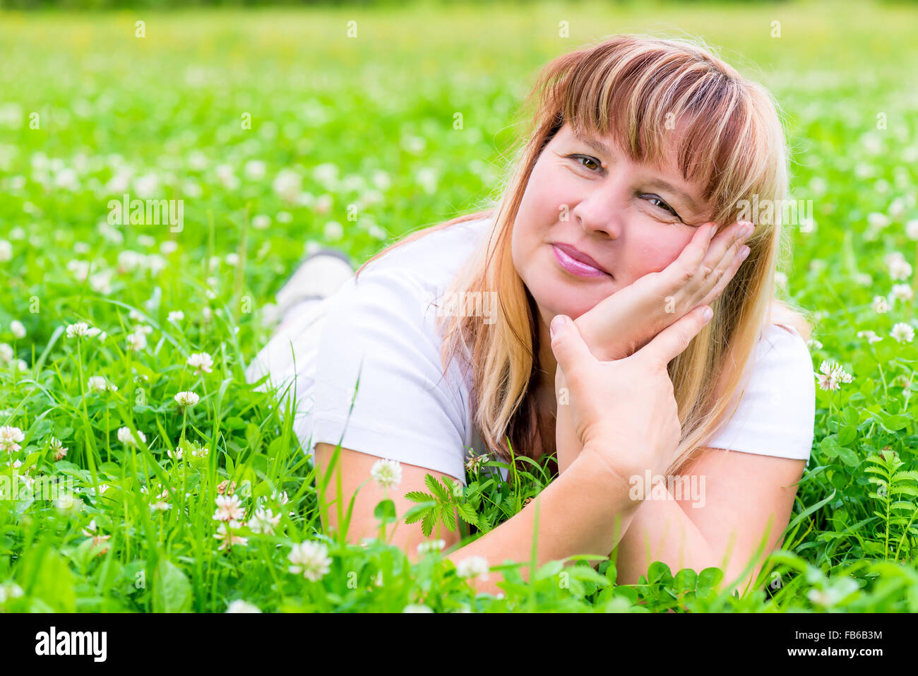 Happy mature woman lying on a meadow and smiling Stock Photo