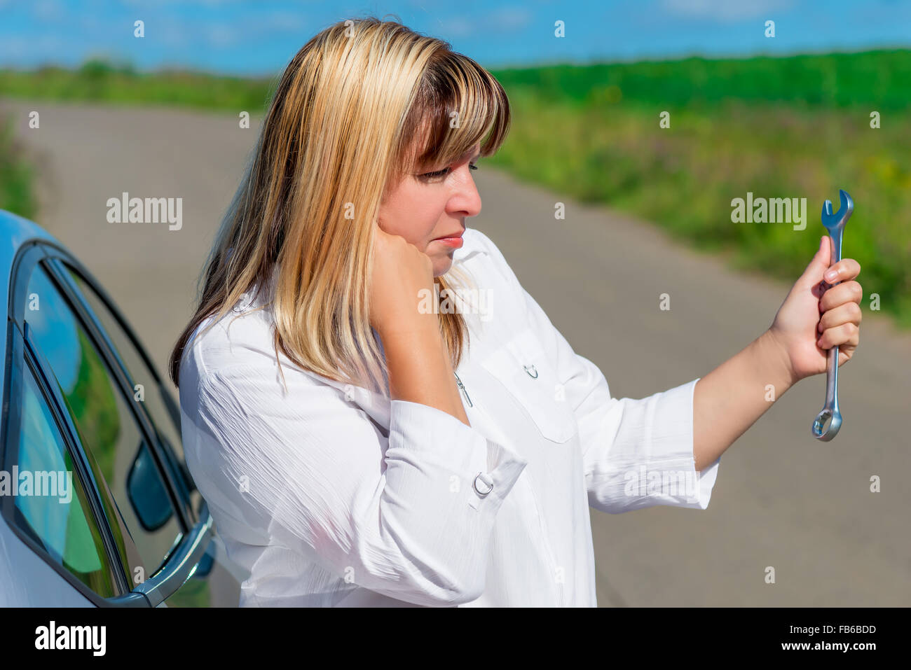 bewildered female driver is looking at spanner Stock Photo