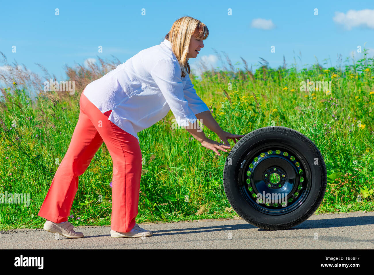 woman on the road on a sunny day with a wheel Stock Photo