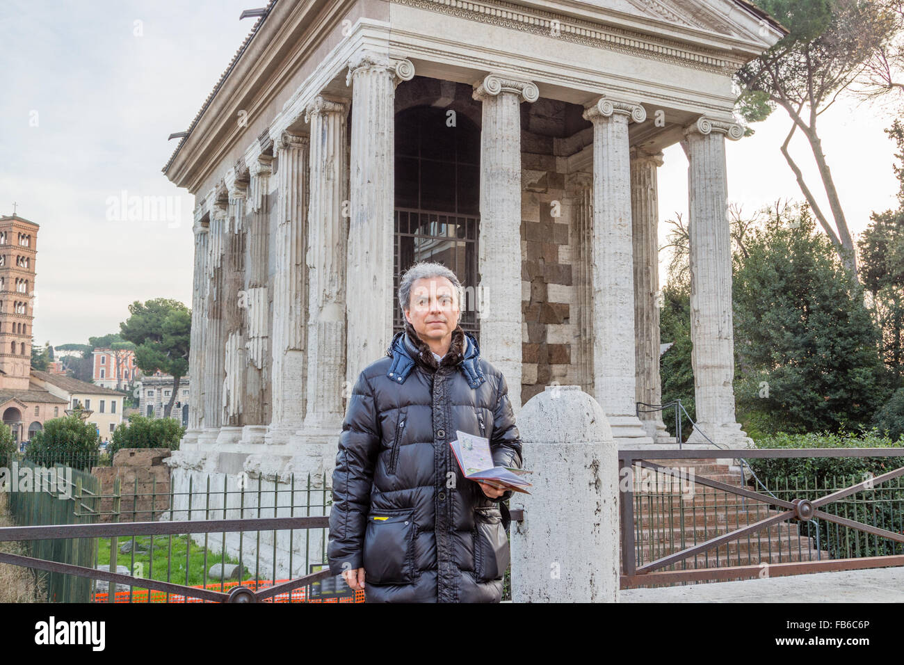 modern man with map near ancient rectangular, tetrastyle, pseudo-peripteral Roman temple of Ionic order in Rome, Italy, dated back to IV century Before Christ Stock Photo