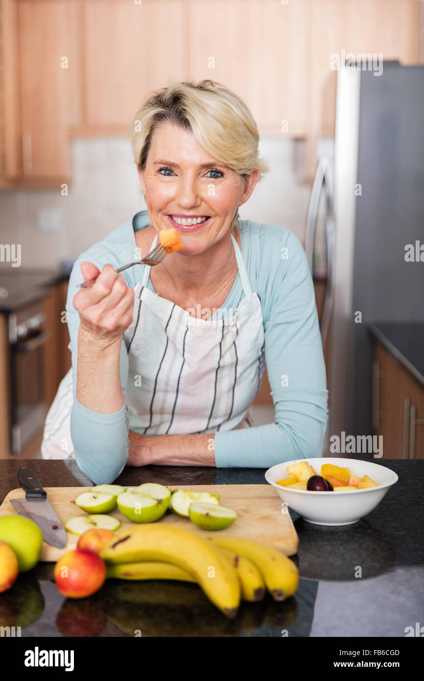 healthy mature woman eating fruit salad at home Stock Photo