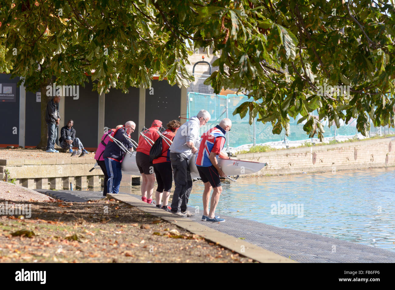 Elderly rowing crew lowering rowing boat into the River Ouse in Bedford