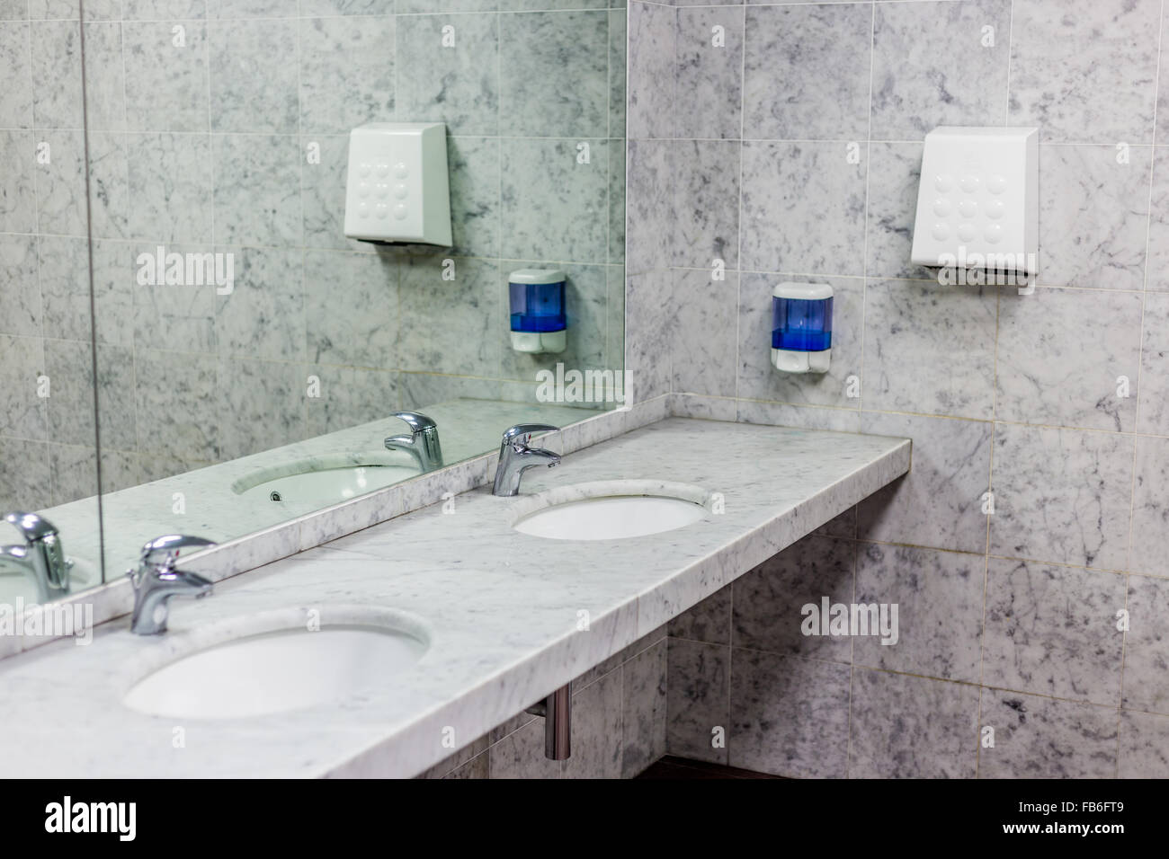 public toilets with mirrors, marble top, soap dispenser and a fan to