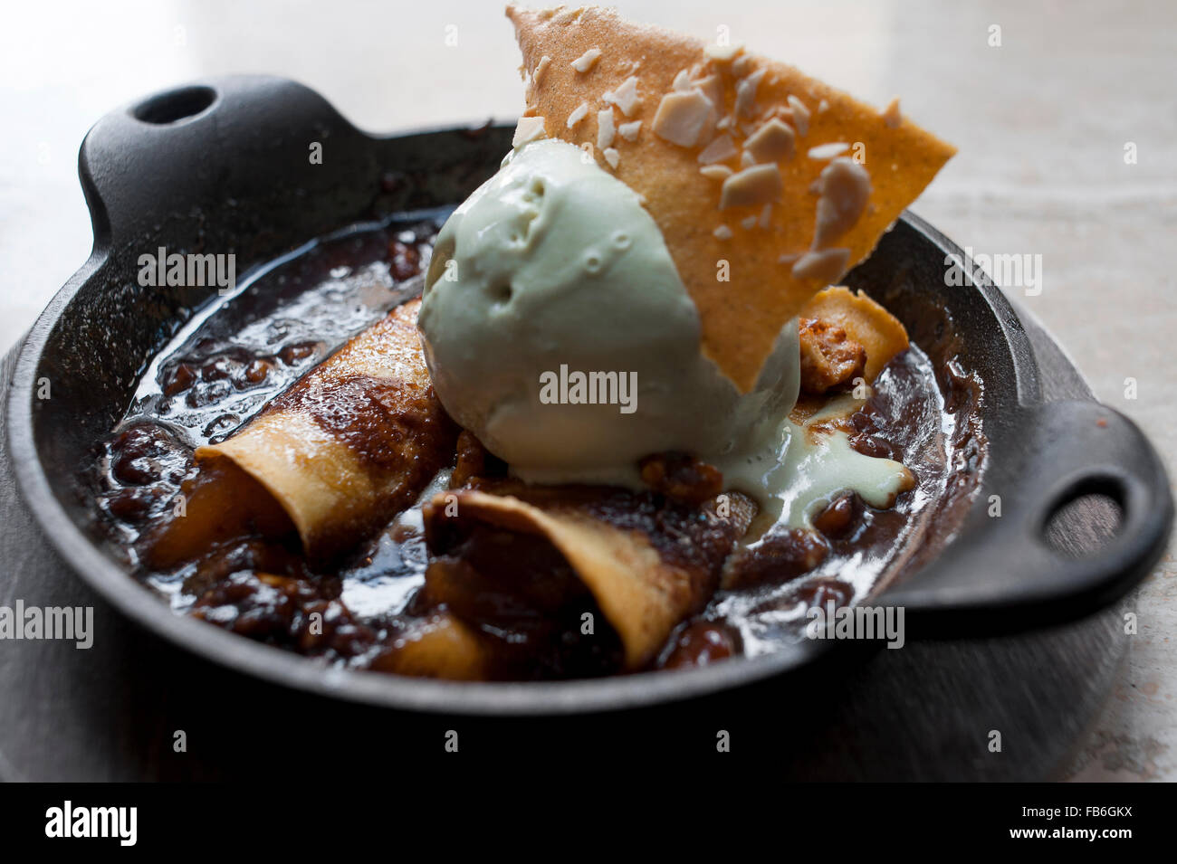 Mint ice cream, wafers and chocolate sauce presented in a black dish in an Italian restaurant. Stock Photo