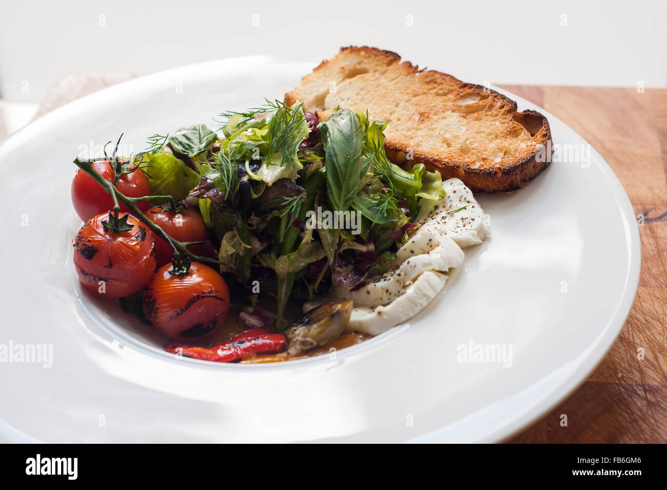 An Italian antipasto dish including bruschetta, grilled cherry tomatoes